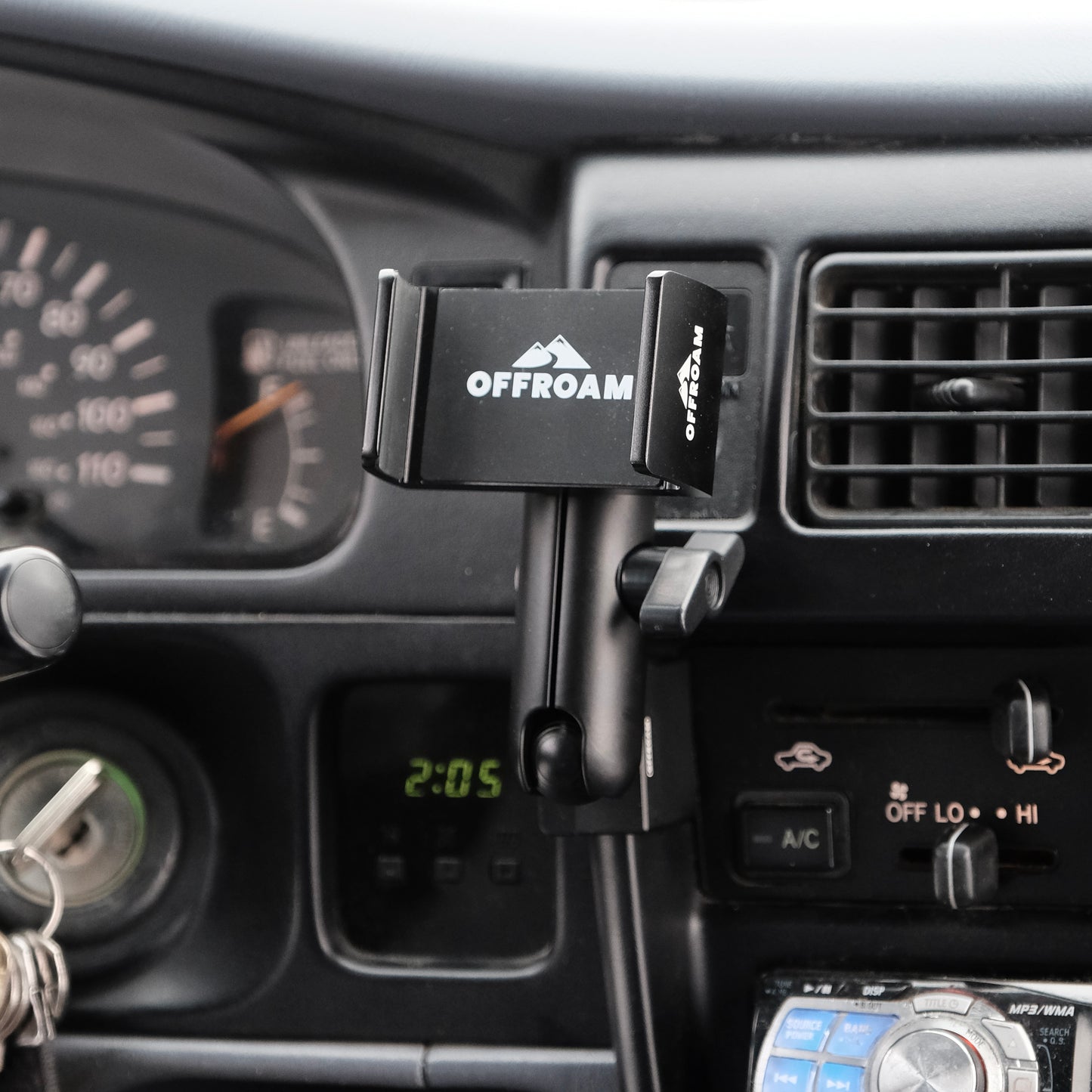 Image of Offroam Phone Mount installed securely in Toyota Tacoma 1996-2004. This premium phone mount installs easily without drilling or glue. Spring loaded Universal holder for use with any phone. Perfect placement without blocking screens, driver view, or air flow. Fully adjustable positioning.