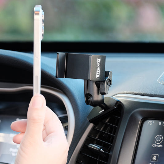 Offroam universal phone mount that accepts any phone and hold securely on any 4 x 4 trail shown installed securely to a air vent bezel of Jeep Cherokee 2014 2018 with a person offering the phone up to show the use of use