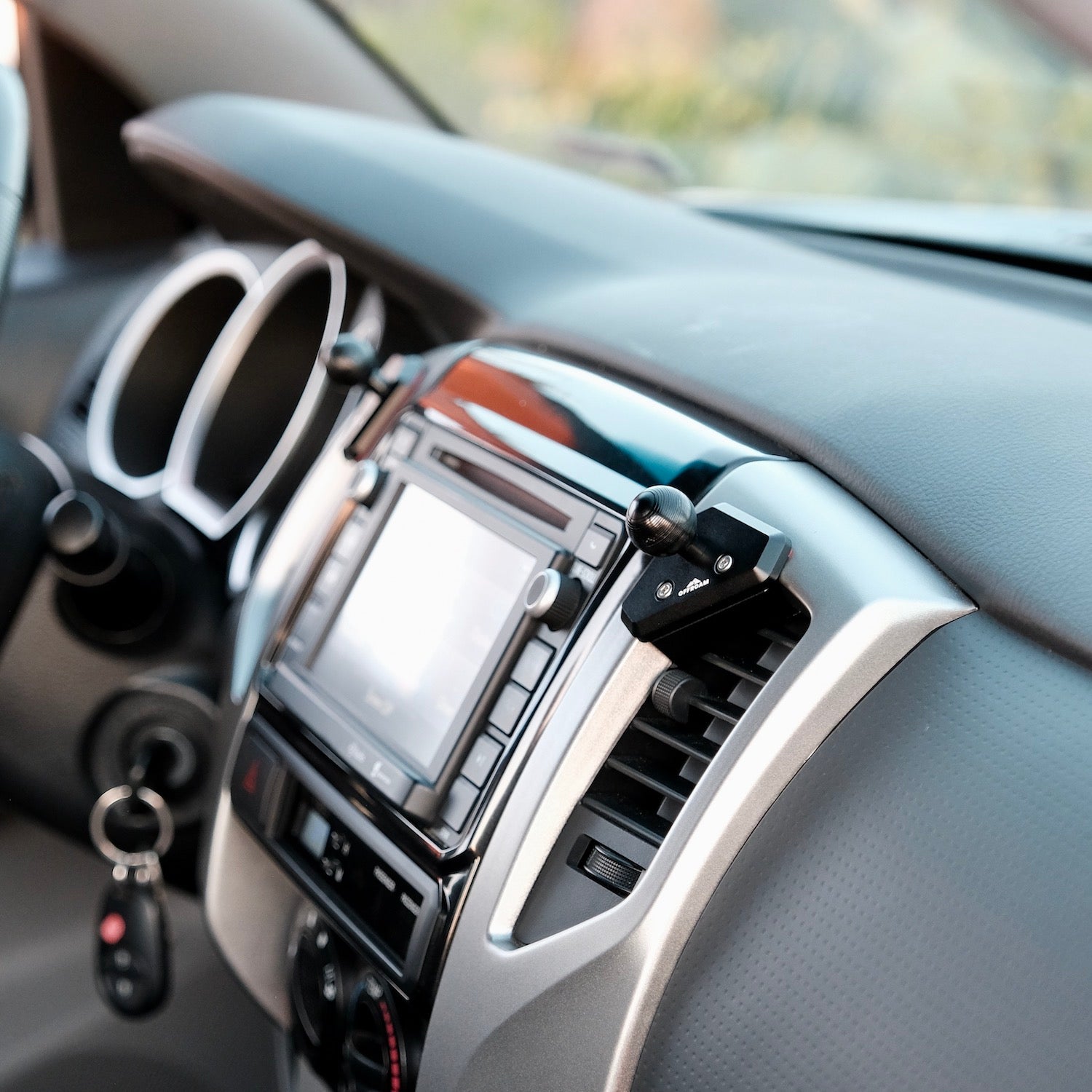 Image of Offroam Mounting Base installed securely in Toyota Tacoma 2012-2015. This premium all metal phone mounting base installs easily without drilling or glue. Perfect placement without blocking screens, driver view, or air flow.