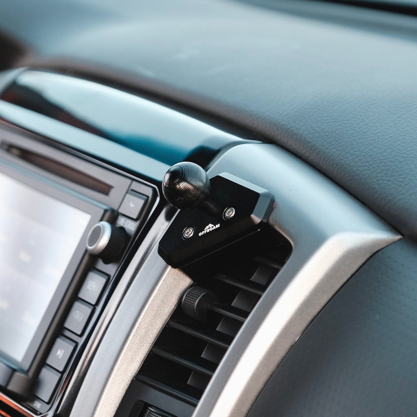 Image of Offroam Mounting Base installed securely in Toyota Tacoma 2012-2015. This premium all metal phone mounting base installs easily without drilling or glue. Perfect placement without blocking screens, driver view, or air flow.