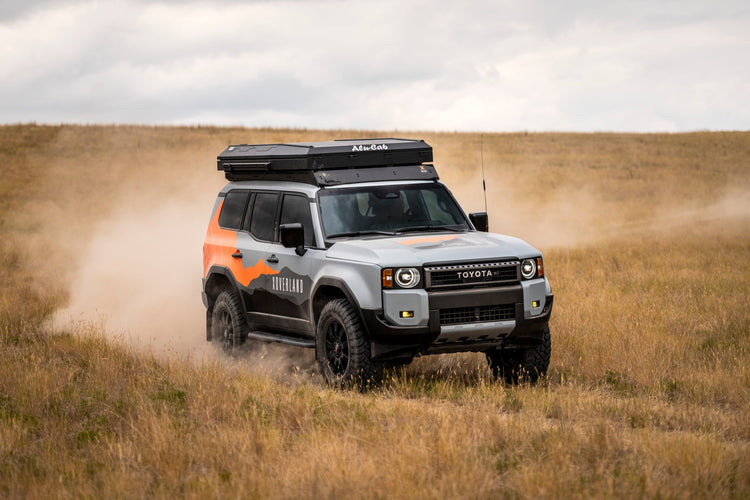 Toyota Land Cruiser 250 2024-2025 offroad driving fully equipped for overland exploration with accessories like roof top tent, phone mount and oversized tires.