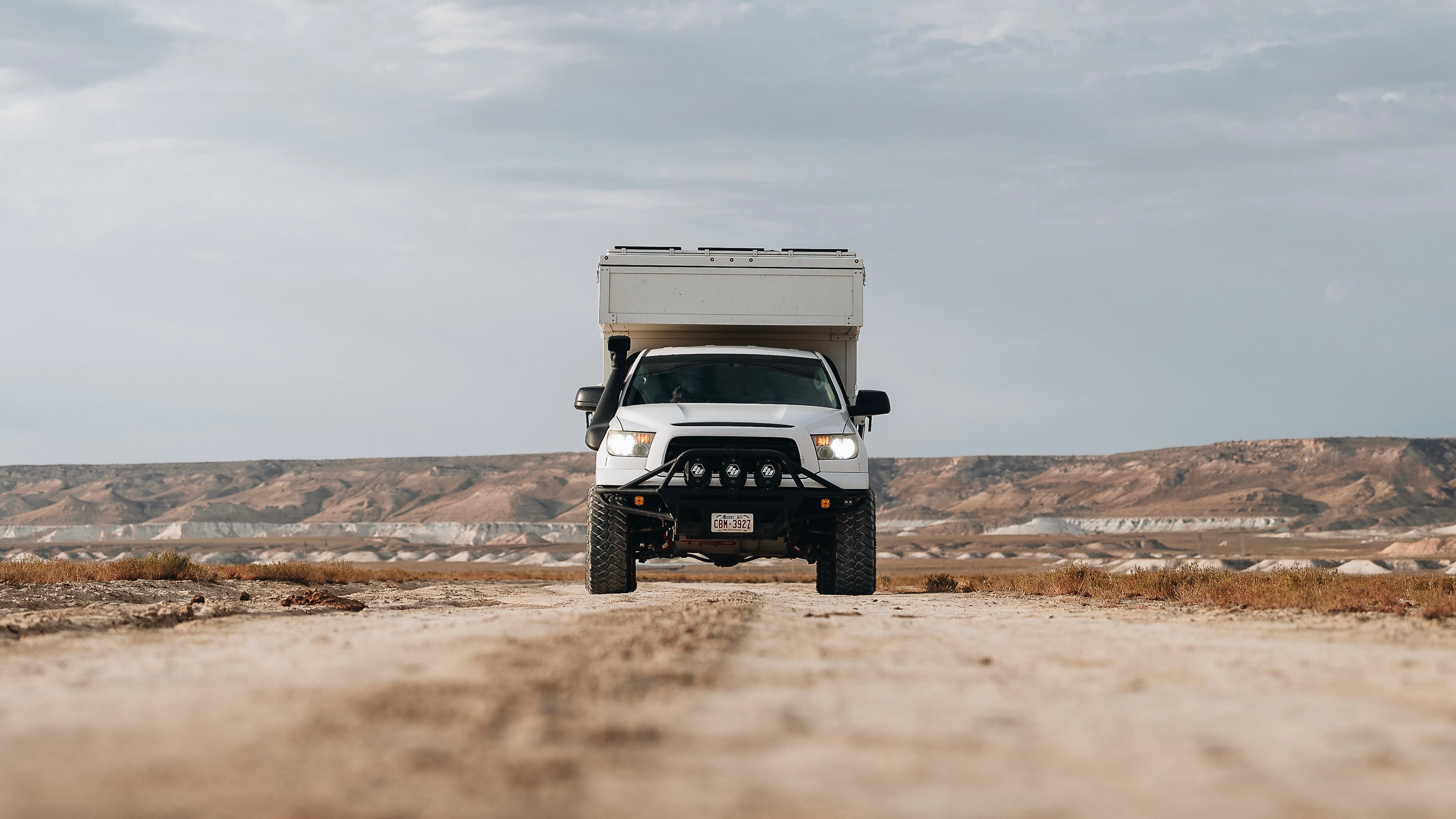 Image of a 2nd generation 2007-2013 Toyota Tundra with a camper owned by Desk to Glory. Shown off-road with an Offroam phone mount installed in the vehicle to help navigate off-road and hold the devices securely on all terrain.