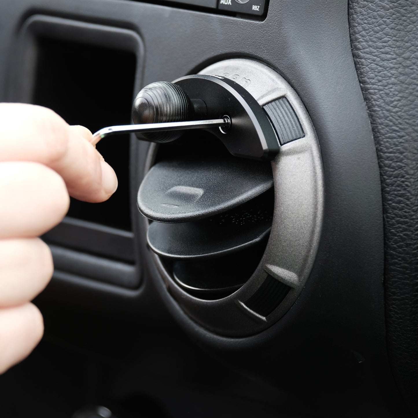 Offroam mounting base with 20mm ball shown being installed in Jeep Wrangler JK 2011-2018 air vent bezel without blocking air flow.