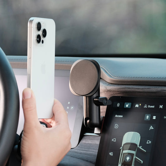 A mounting base installed securely in Rivian R1T R1S behind the screen using existing features of the dashboard. The base and a coupling arm are premium accessories that allows to securely mount a phone holder with MagSafe magnets.